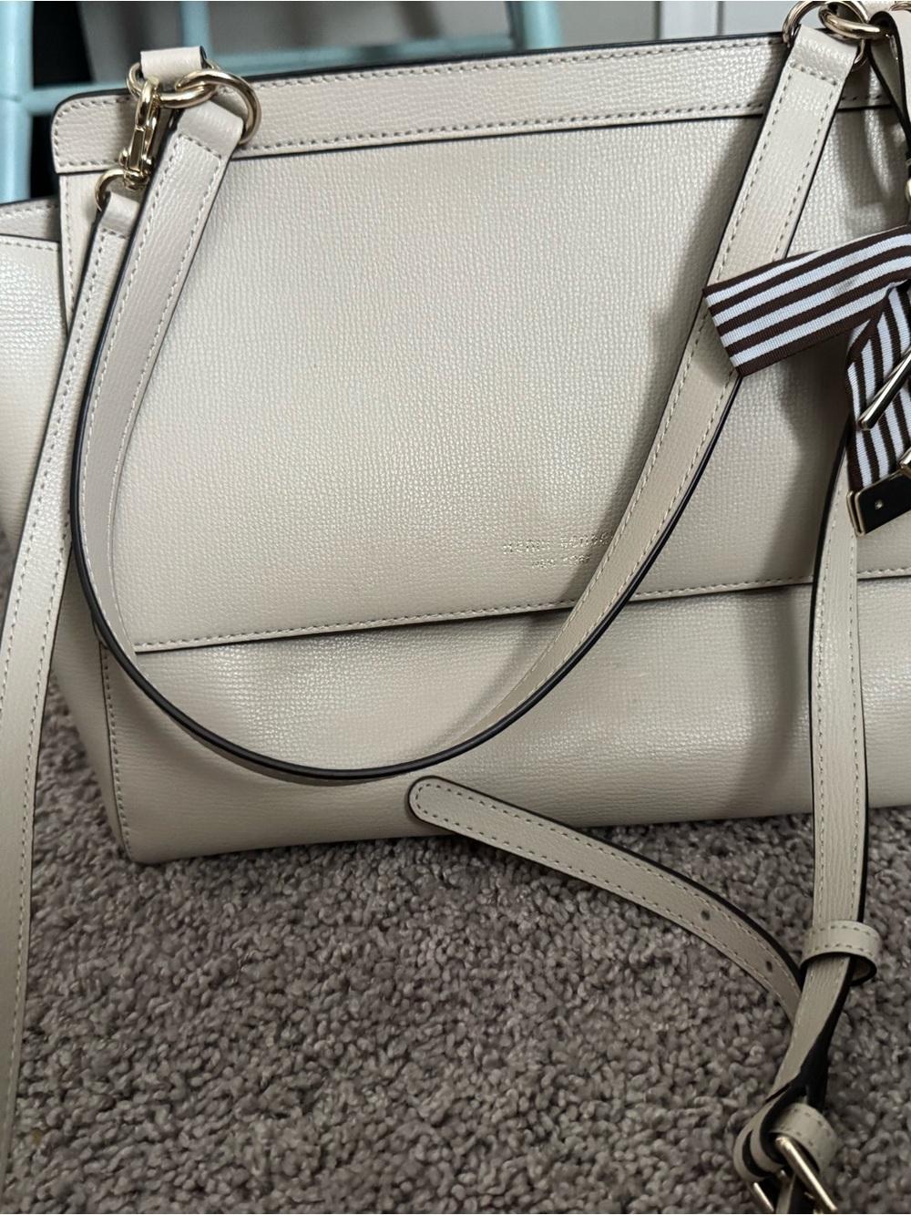 Henri Bendel beige leather handbag featuring a signature striped ribbon charm